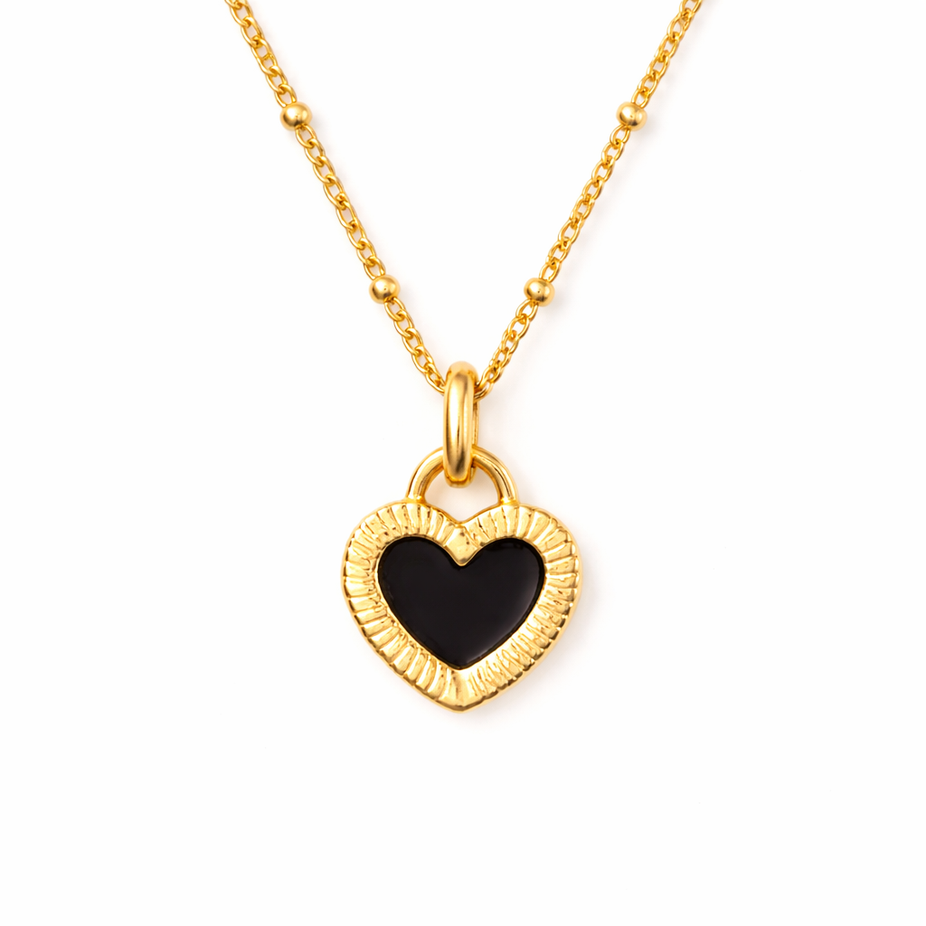 Gold necklace with black heart pendant on white background