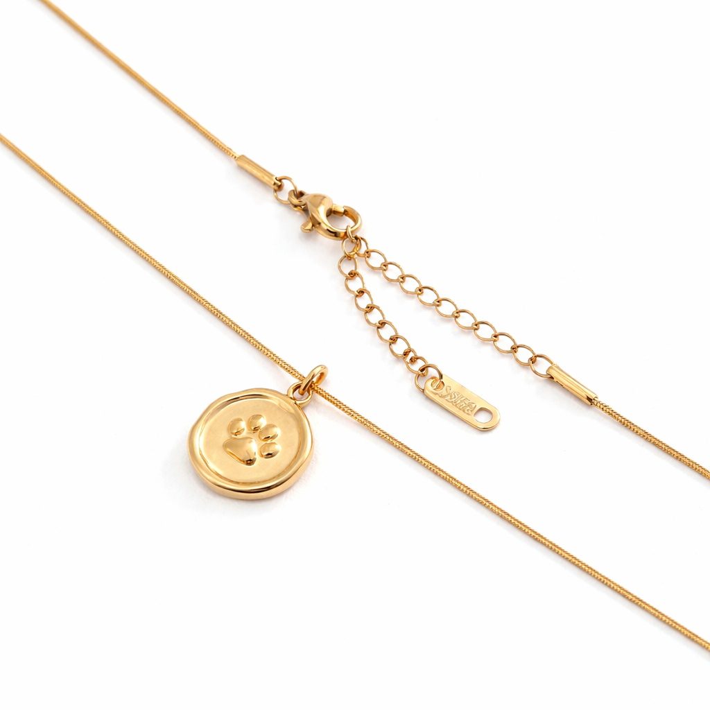 Gold paw print pendant necklace on white background