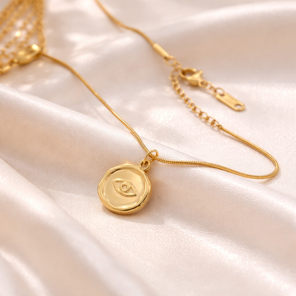 Gold eye pendant necklace on satin fabric at an angle