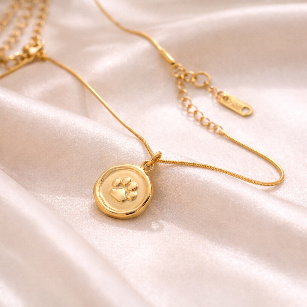 Gold paw print pendant necklace on soft satin fabric