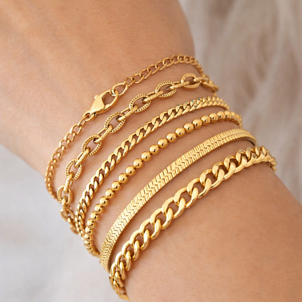 Gold chain-link bracelet with textured oval links showcased on a woman’s wrist, styled alongside four additional gold bracelets, with the featured bracelet placed prominently at the center for emphasis.